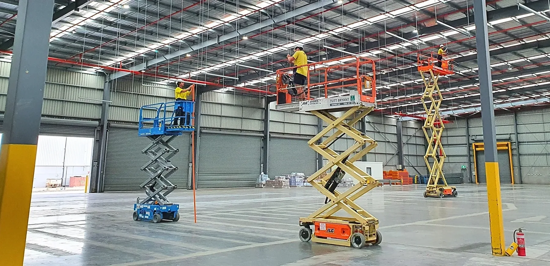 Field crews working from scissor lifts inside a large facility